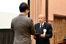 　「地域貢献大賞」の表彰式で日本新聞協会の中村史郎会長（左）から大賞の記念の盾を受け取る北國新聞宝立販売所の船本寛所長＝２０日午後、東京都千代田区