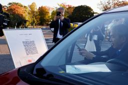 　車中泊避難の実証実験で、スマートフォンを使って受け付けをする参加者＝２２日午後、熊本市