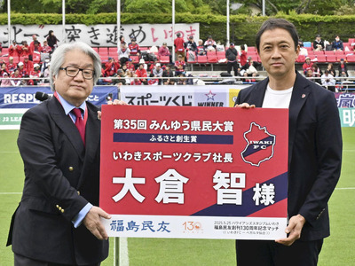 みんゆう県民大賞を受賞し、野崎社長から記念ボードを受ける大倉さん（右）＝２５日、いわき市・ハワイアンズスタジアムいわき