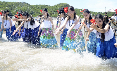 フラの衣装で海と戯れる高校生＝１９日午前、薄磯海水浴場