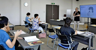 吉田会長の動きに合わせて手話を学ぶ参加者
