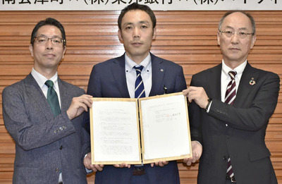 協定書を手にする（左から）下村社長、二瓶副町長、菊地常務執行役員