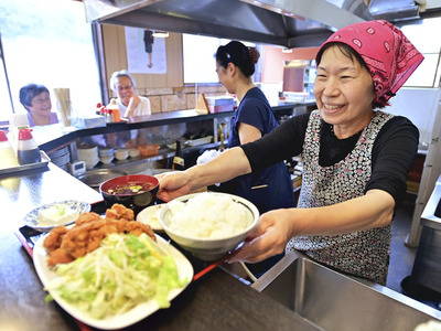 客の注文品を出す吉田さん（右）。「１００歳まで店をやるんだから」と宣言する