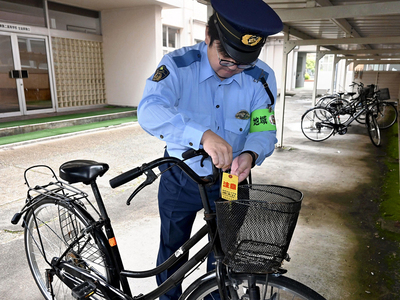 無施錠の自転車にイエローカードを取り付ける署員