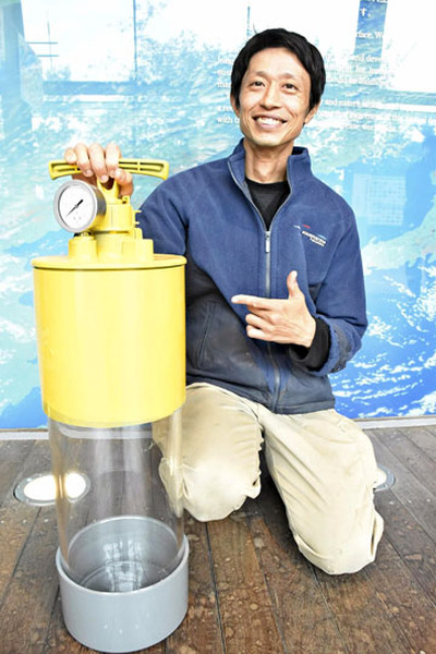 特許を取得した吉村さんと水中生物収容装置のデモ機