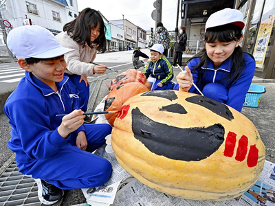 ジャンボカボチャに絵の具でイラストを描き入れる児童ら=29日午後、二本松市