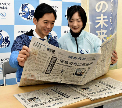 市長選の結果を伝える新聞に目を通す馬場さん（左）と妻菜里さん