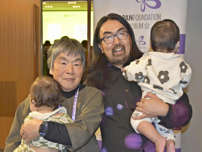 双子の子どもを抱きかかえる荒川ナッシュ医さん（右）と、製作に参加した母美和子さん