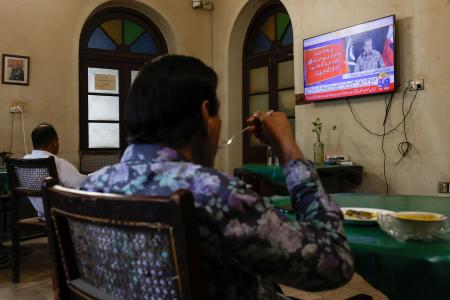 　パキスタン軍の記者会見を報じるテレビを見る人たち＝１０日、パキスタン南部カラチ（ロイター＝共同）