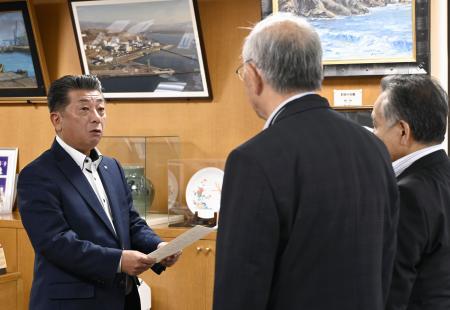 北海道泊村議会の議長らから意見書を受け取る高橋鉄徳村長(左)=31日午前、北海道泊村